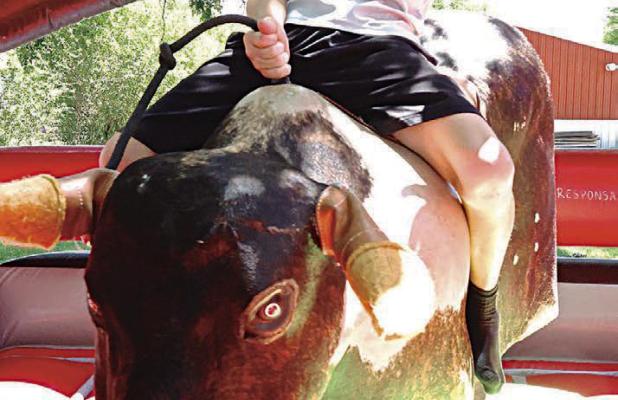 Jaxson Heinrich, 10, Scott City, gets a full eight second ride and a little more at the bull riding station at Patton Park last Saturday. It was one of the activities held in conjunction with the Blue on Blue event sponsored by law enforcement. (Record Ph