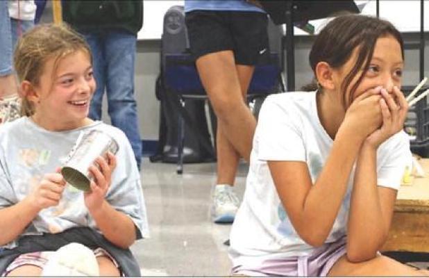 Scott City Middle School fifth graders Hartley Berry (left) and Ashley Myers share a laugh as they perform as part of Thad Beach’s bucket band last Friday morning. Beach conducted a weeklong musical residency at SCMS, sponsored by the Scott County Arts 