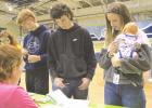 Volunteer Janet Harkness provides assistance to married couple Brandon Smyth and Shasta Hope, along with their child, as they figure expenses at the food booth. (Record Photo) a glimpse of reality