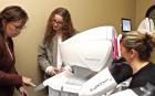 SCHS junior Erika Felker (center) listens to optometry technician Elizabeth Cox explain the procedure for giving a patient an exam at the Scott City Eye Center. (Record Photo) growing our own