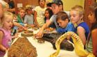 Youngsters gather around a table so they can get a closer view of fossil replicas and models that were part of the program provided by Jake Mishoulam with the Sternberg Museum. (Record Photo) Sternberg brings fossil exhibit to SC Library
