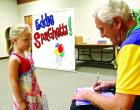 Eddie Bisiar (aka Eddie Spaghetti) autographs a copy of his book for fiveyear-old Lydia Nichols following his performance. (Record Photo) Eddie’s musical career has gone from flower to library children