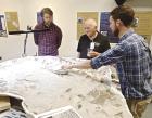 Kris Super (right), director of the Western Kansas Fossil Lab, and fellow paleontologist Mike Everhart (center) discuss aspects of the elasmosaurus fossil that Super discovered in the Smoky Hill Basin. (Record Photo)