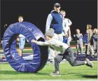 Jude McNary chases down a tackling ring while Scott Community High School football assistant coach Colborn Couchman looks on during a “skills and drills” night involving the SCHS football team and their Beaver Brothers. About 55 youth from kindergarte