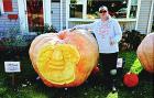 Joe Adkins in front of his home with one of the giant pumpkins he grew and then carved. Adkins’ love of pumpkin-carving eventually led him to grow the giant gourds.