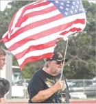 Jack Thornton holds the American flag during the playing of the national anthem prior to the start of last Friday’s Scott Community High School football game. The Vietnam War veteran was among several local residents honored during the annual Military N paying tribute to military veterans