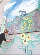 Local artist Meghan Isaacson adds some finishing touches to a recently completed mural located on the west 400 block of K96 Highway in Scott City. (Record Photo)