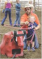 Quinn Meyer, 1-1/2-yearsold, of Scott City, is able to successfully lasso a dummy steer with help from his uncle, Danny Koons. The duo teamed up during a break between the barrel racing and jackpot team roping at the county fairgrounds on Saturday evening