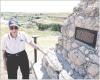 With Battle Canyon in the background, Dennie Siegrist stands by the monument that gives a brief description of events that occurred at the historic site. (Record Photo)